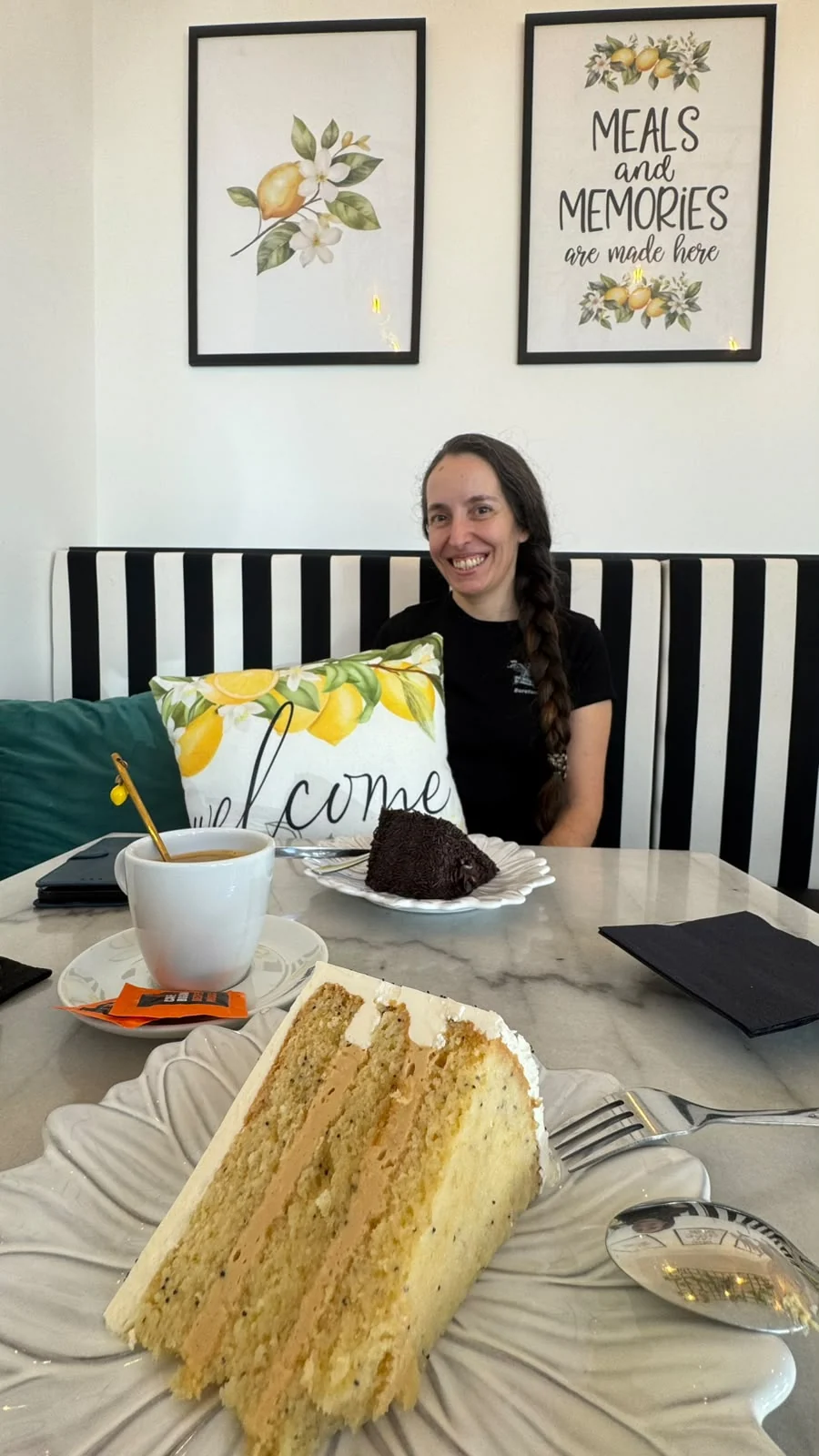 Sofia sentada à mesa na Confeitaria Limão Papoila com bolos em primeiro plano